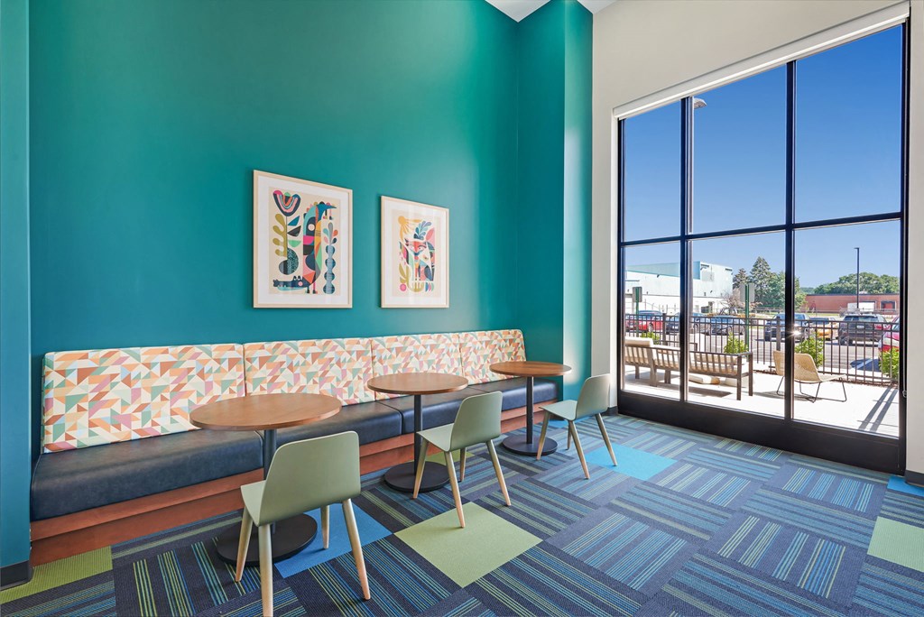 a lounge area with tables and chairs and a large window