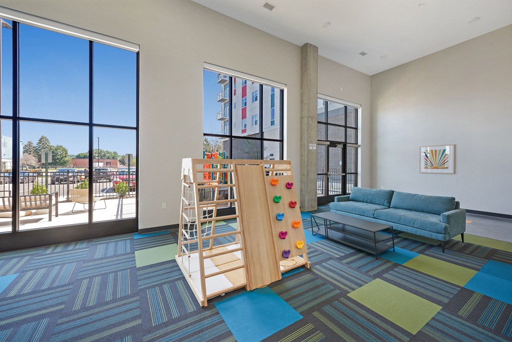 a living room with a childs play area and large windows