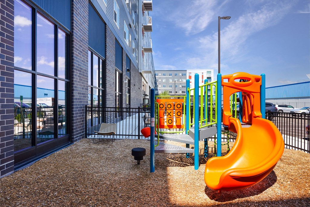 a playground with a slide and other toys in front of a building