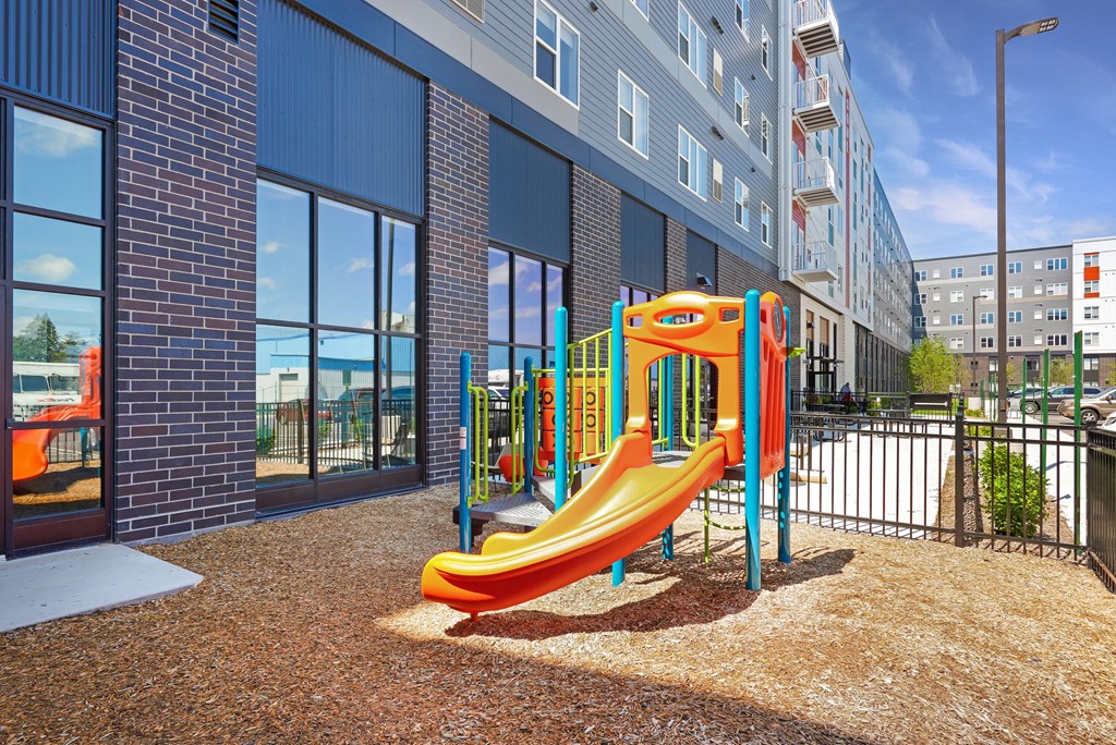a playground at a building with a yellow slide