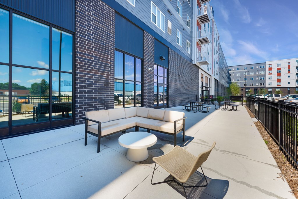 a patio with couches and a coffee table in front of a building