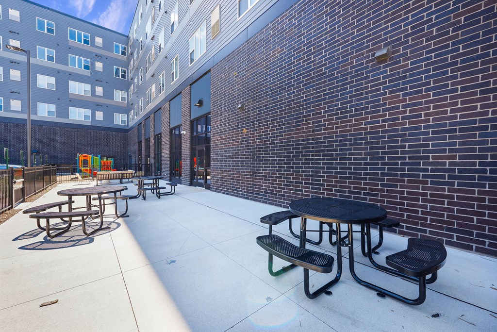 a patio with tables and chairs outside of a brick building