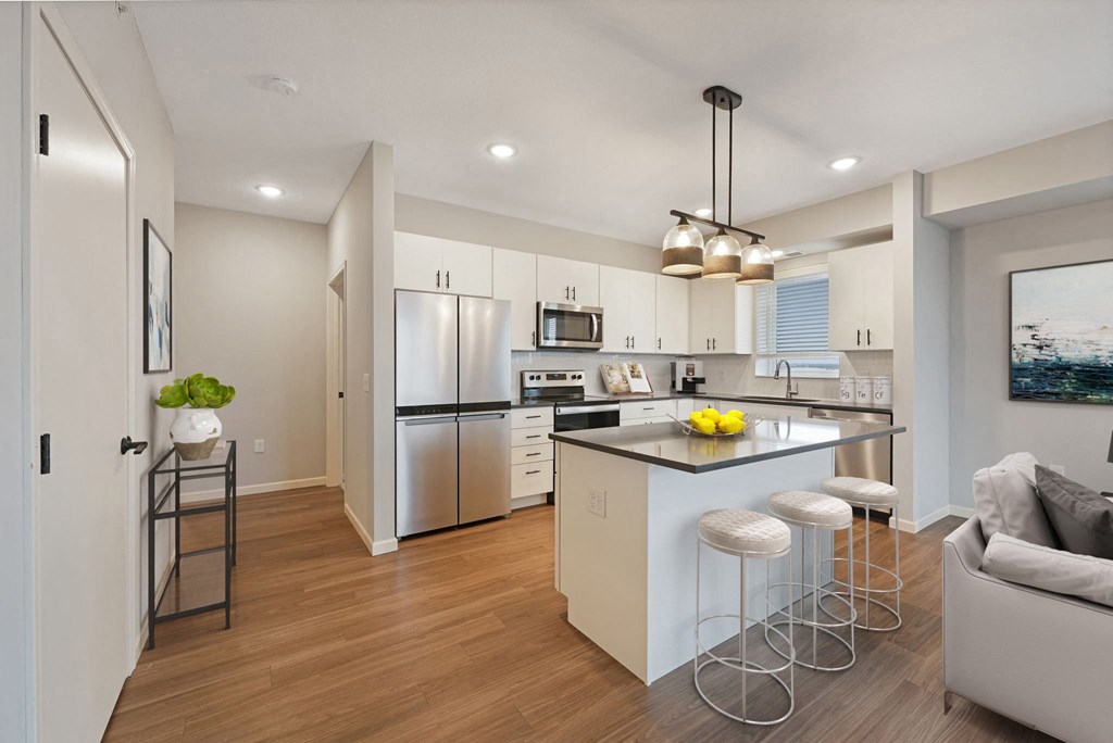 an open kitchen and living room with an island and stools