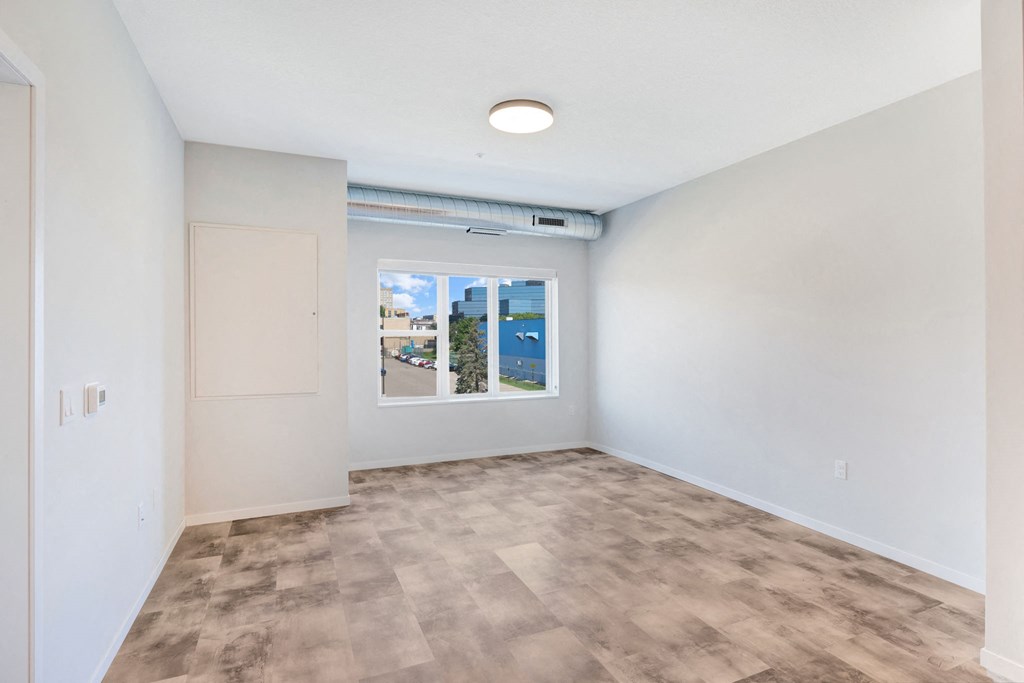 an empty living room with a window and white walls