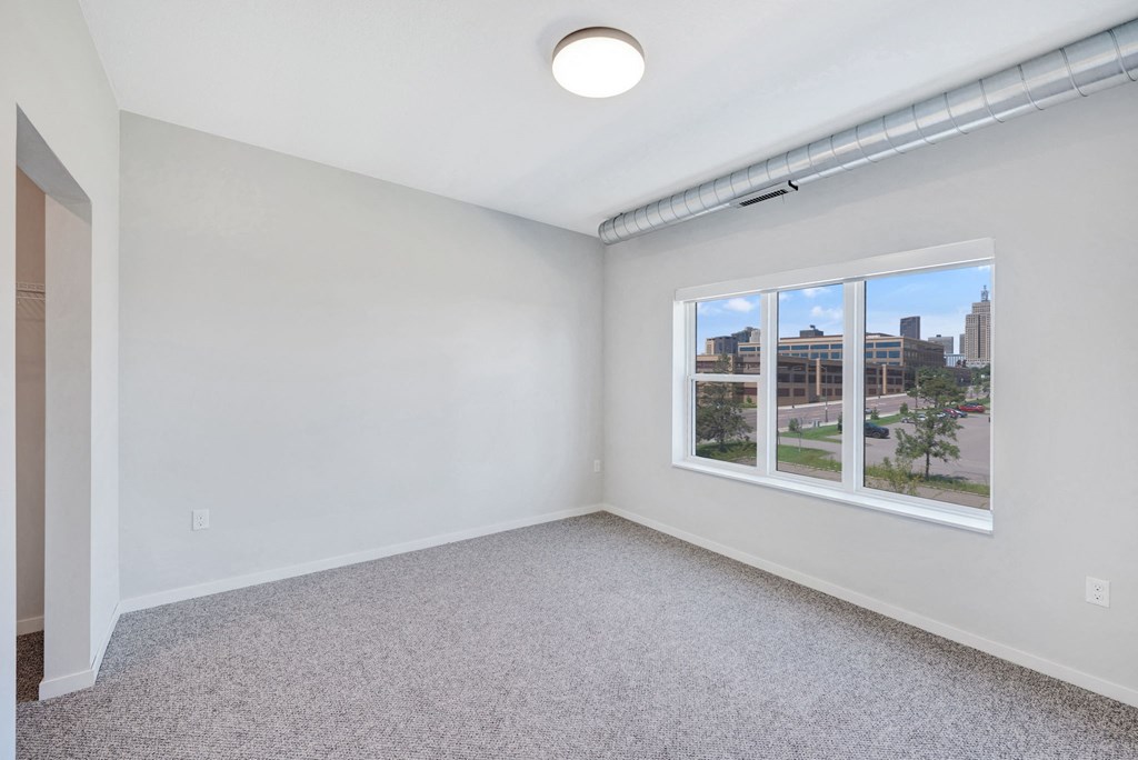 an empty room with a window and a carpeted floor