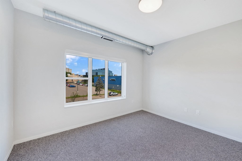 a bedroom with a window and a carpeted floor