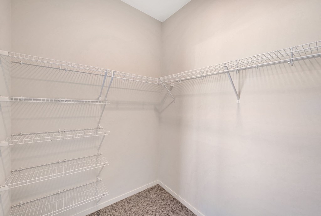 the closet of a bedroom with two shelves in it and white walls