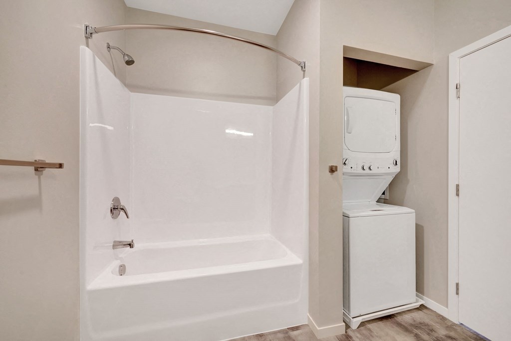 a white bathroom with a shower and a washer and dryer in it
