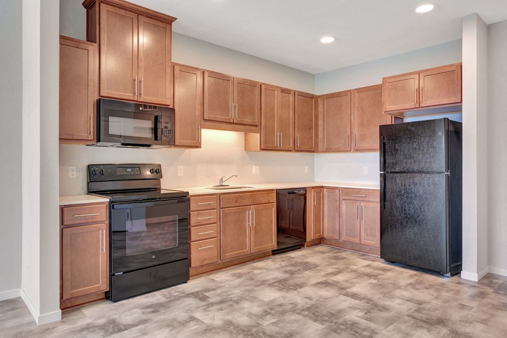 an empty kitchen with wood cabinets and black appliances