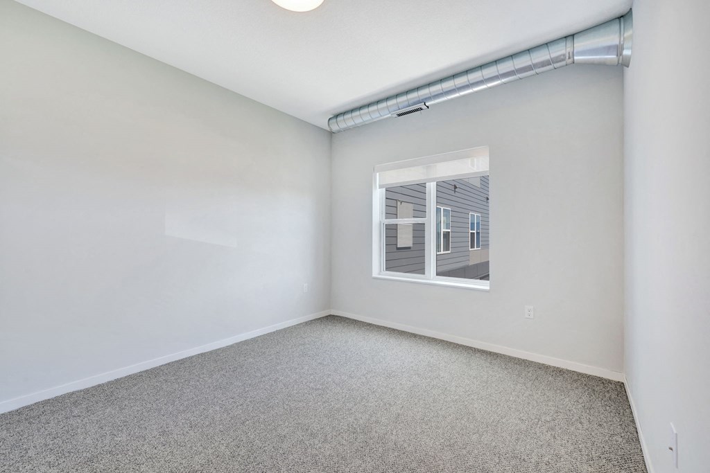 an empty room with a window and white walls