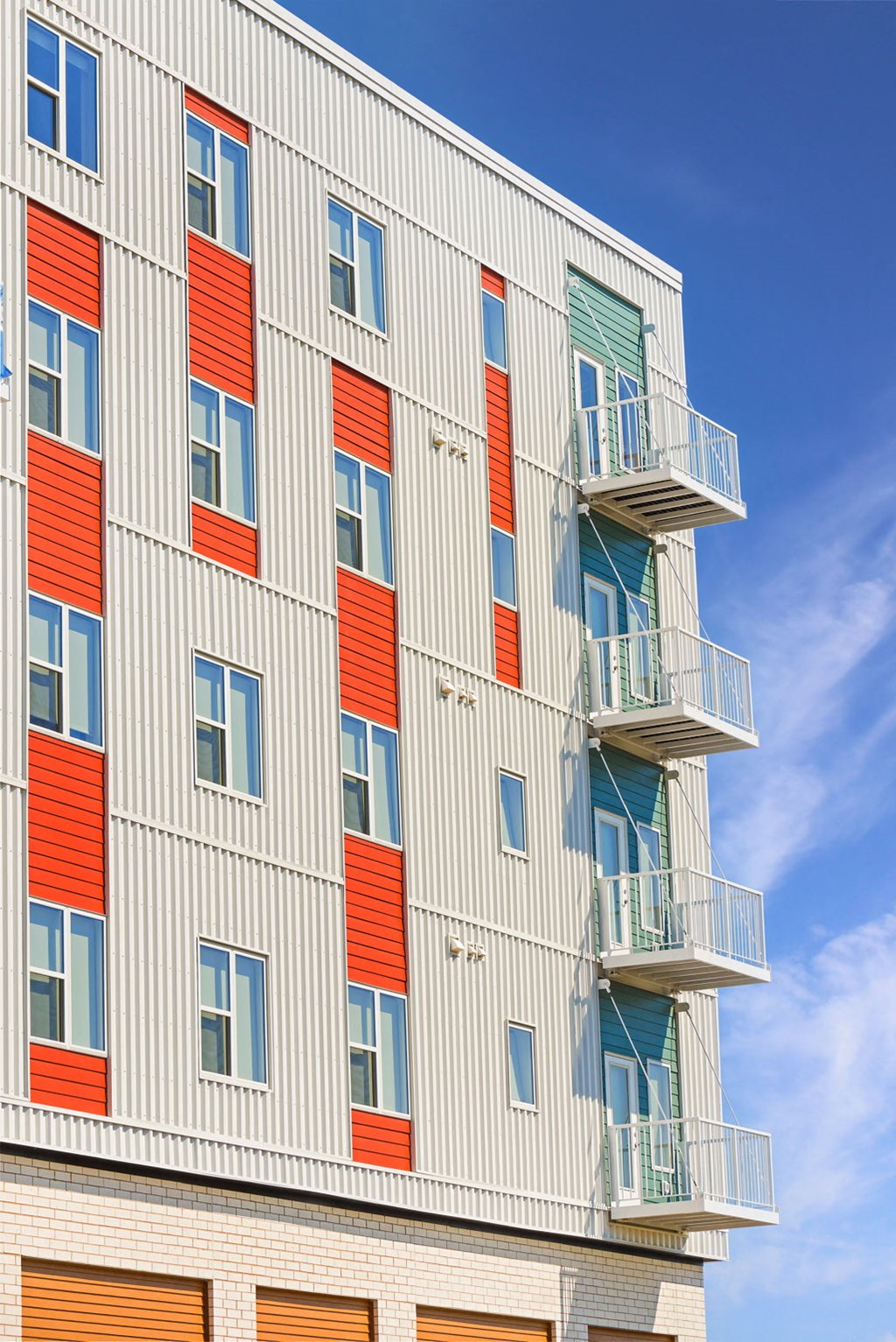 a tall building with red and white facade and balconies