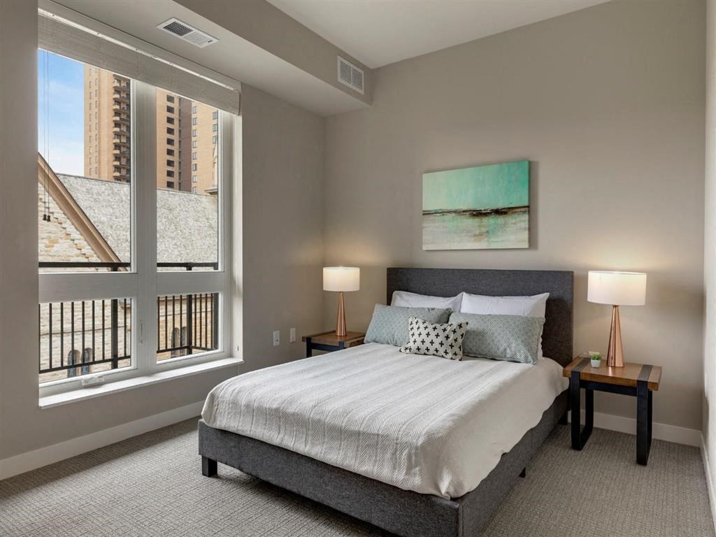 Carpeted bedroom with bed, nightstands and lamps