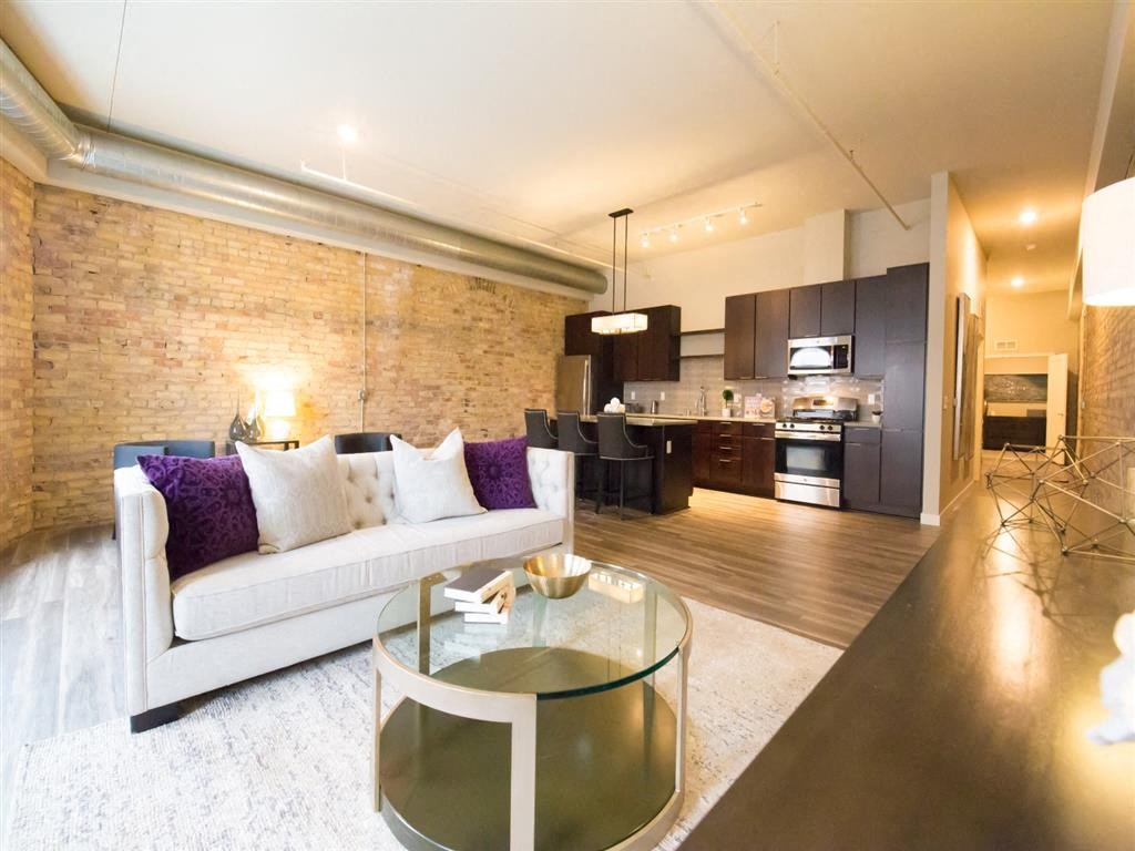 open concept living space with exposed brick and high ceilings