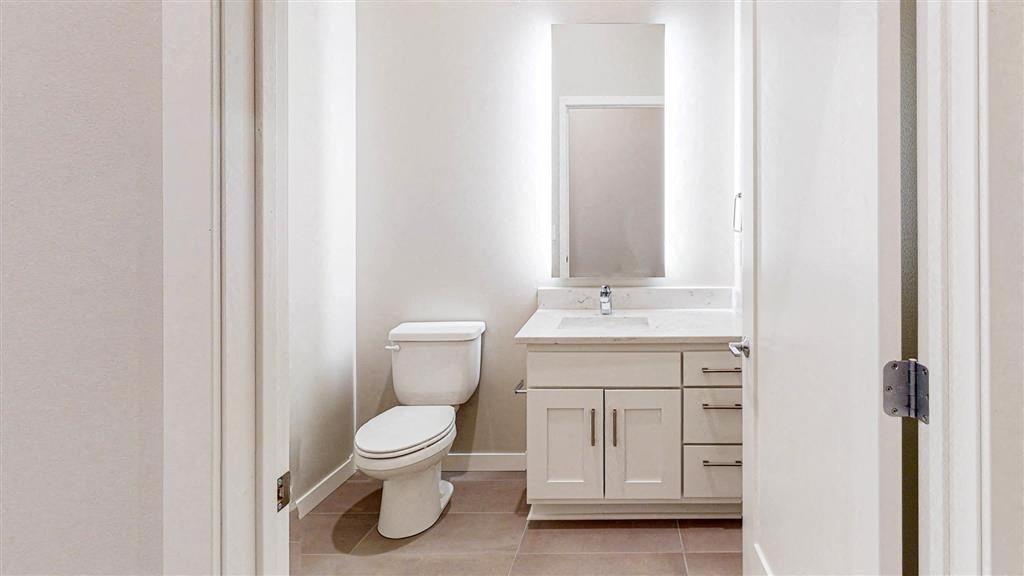 bathroom vanity and toilet with backlit mirror