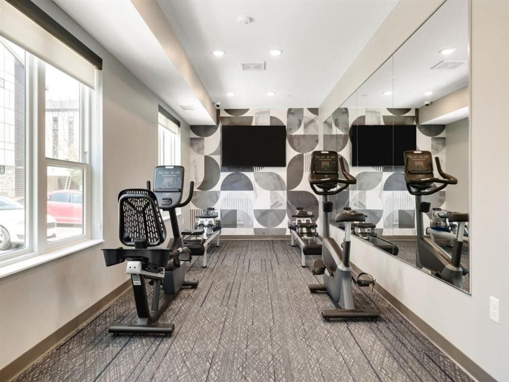a gym with treadmills and monitors on the wall