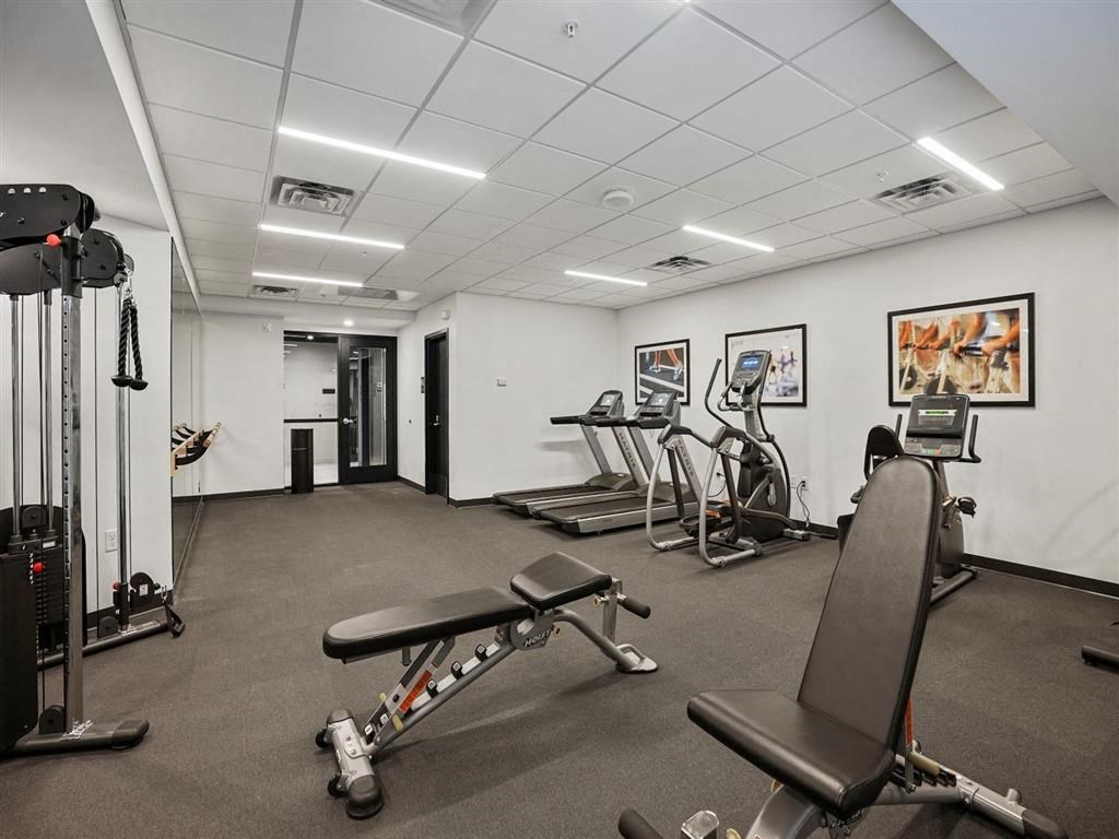 a room with a lot of exercise equipment and paintings on the wall