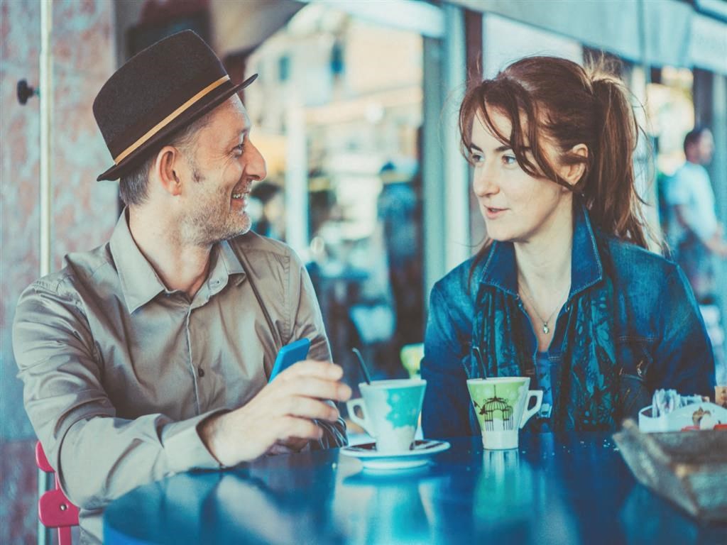 a man and a woman sitting at a table in a cafe