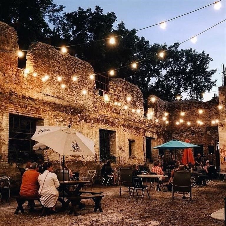 a group of people sitting at tables under string lights