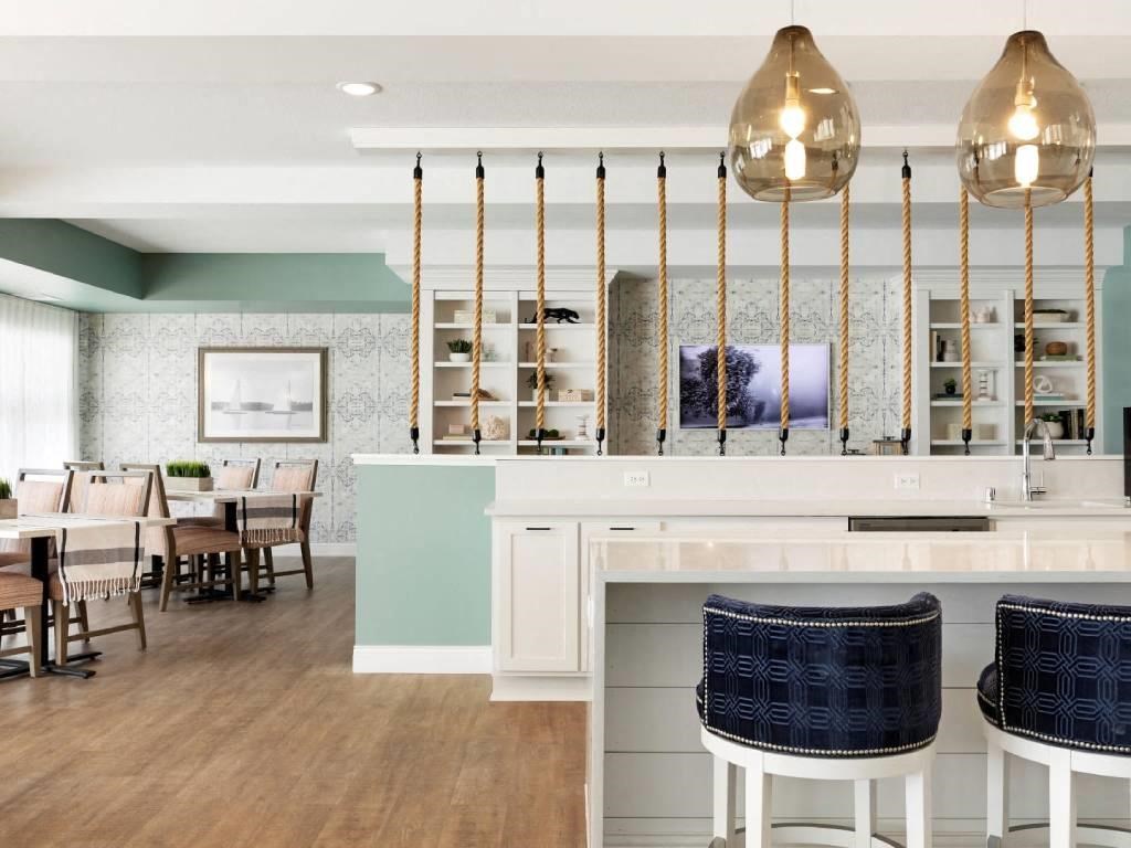 Clubroom with white kitchen, nautical rope decoration and tables and chairs