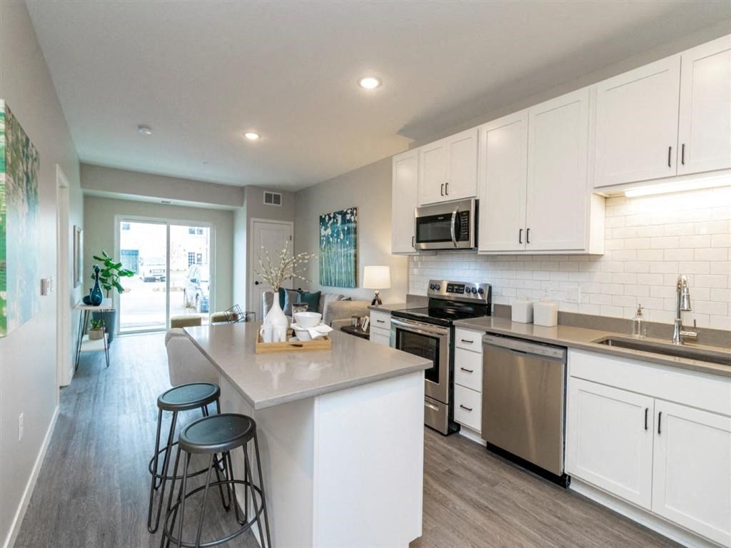 kitchen with white cabinets, island and stainless steel appliances open to living room