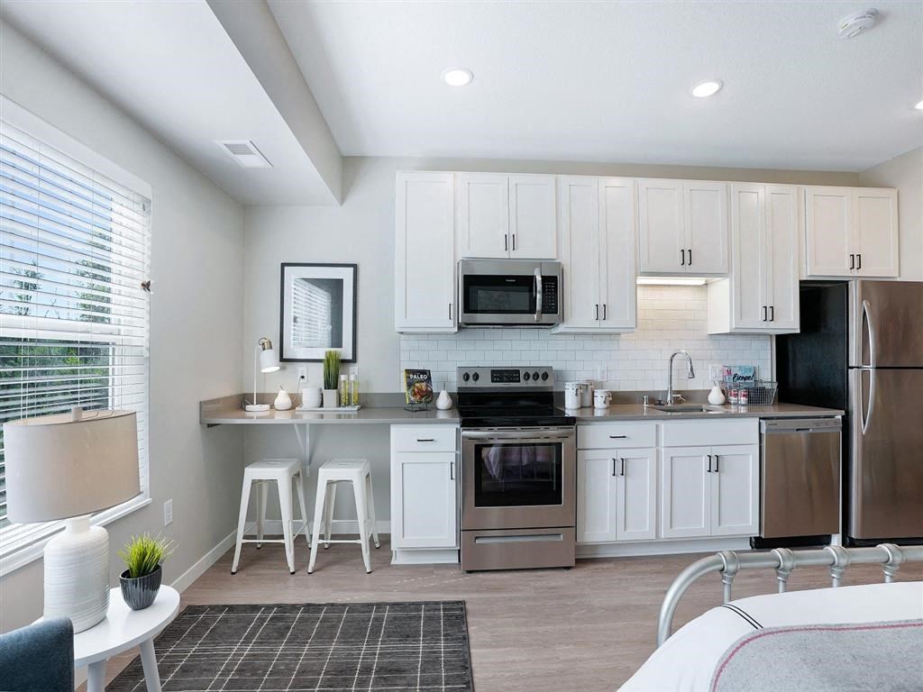 Studio kitchen with white cabinets and work from home desk