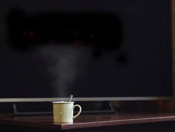 a coffee cup sitting on a table in front of a tv