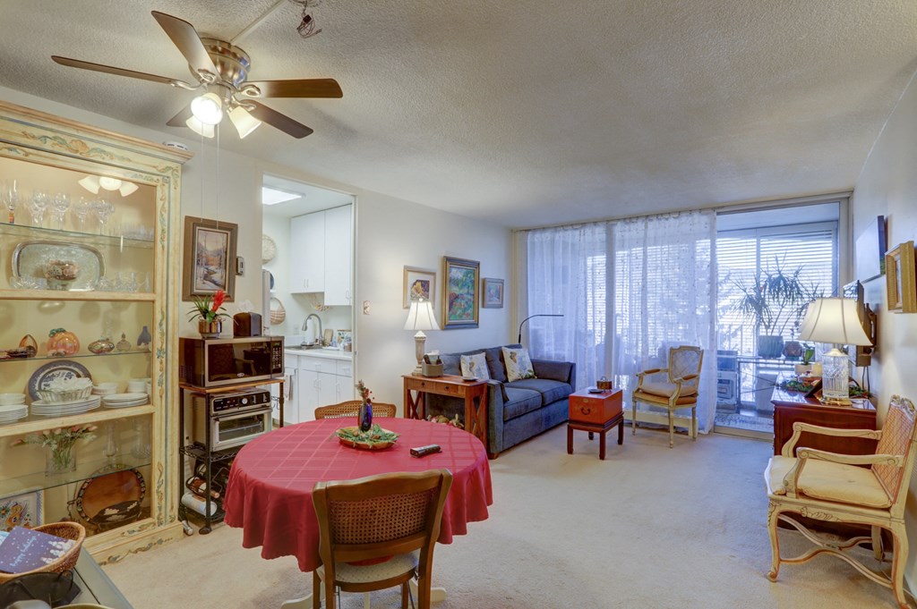 a living room with a table and a ceiling fan