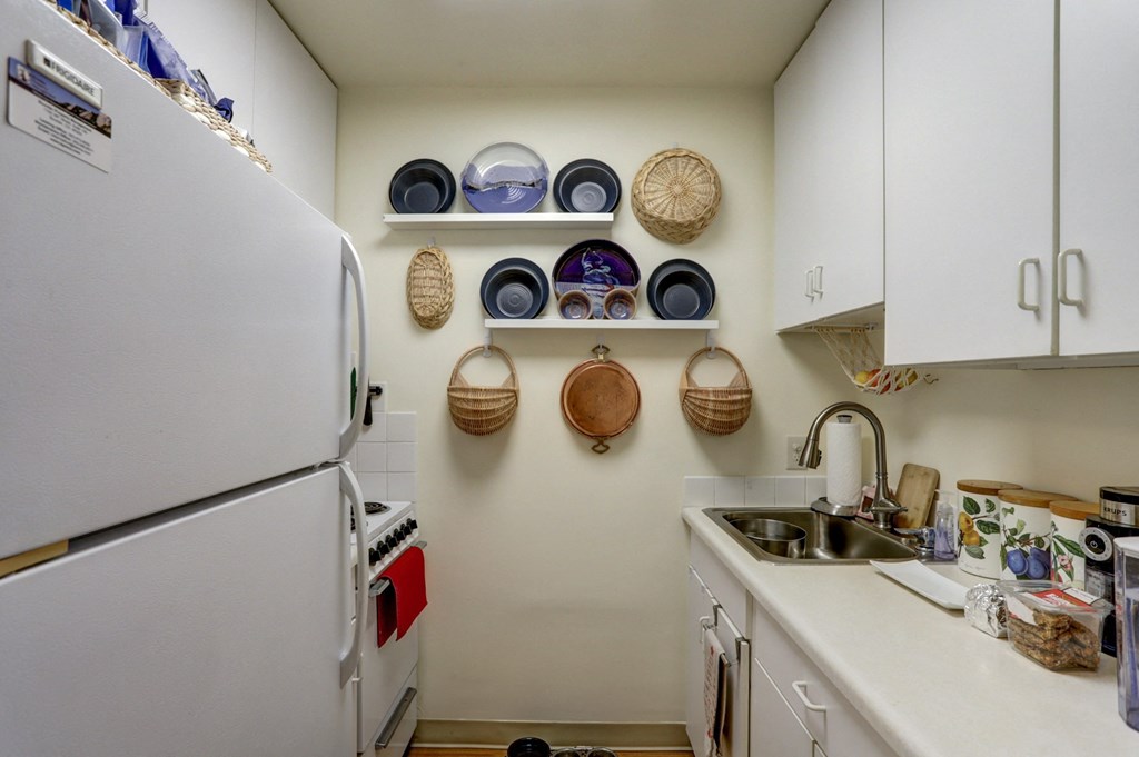 a kitchen with a sink and refrigerator and white cabinets