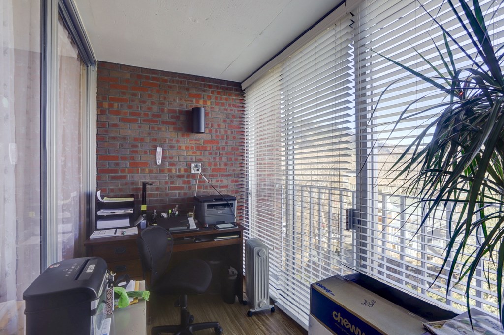 an office with a brick wall and a window with a desk and a printer