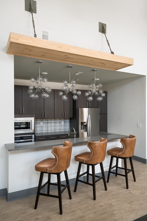 A kitchen with a bar area and three brown chairs.