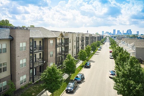 A long street with cars parked on the side and apartment buildings on both sides.