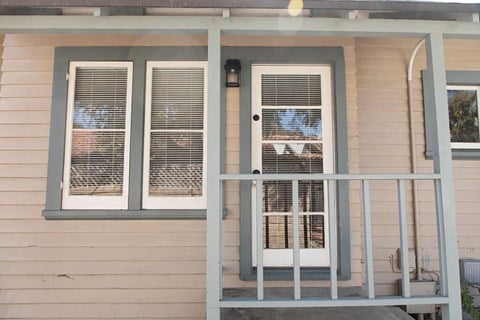 A house with a white door and two windows with white shutters.