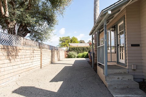 A house with a grey door and a concrete pathway leading to it.