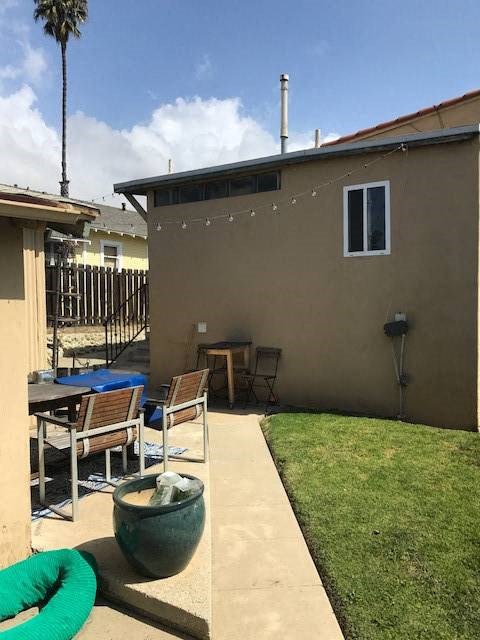 A patio with a table and chairs is surrounded by a green hose.