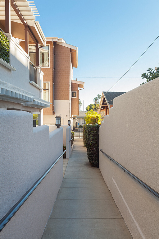 A narrow alley with a white wall on one side and a building on the other.