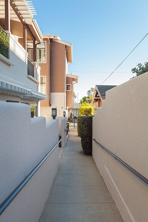 A narrow alley with a white wall on one side and a building on the other.
