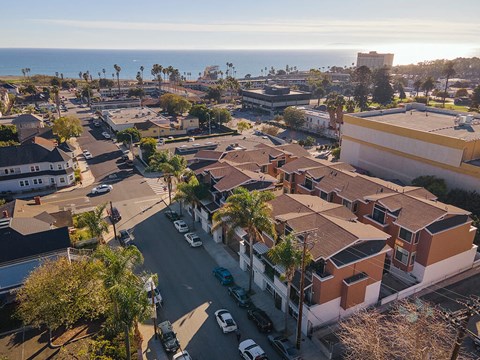 A sunny day in a residential area with houses and parked cars.