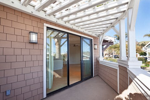 A patio with a white pergola and a glass door.