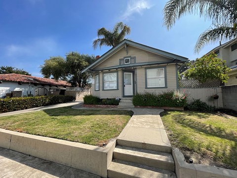 A house with a front yard and a concrete pathway leading to the front door.