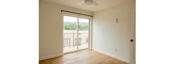A room with a sliding glass door leading to a balcony.
