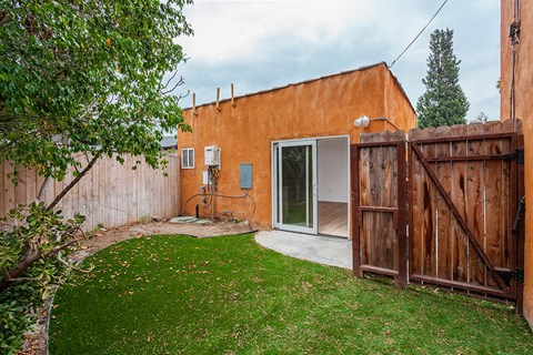 A backyard with a brown fence and a green lawn.
