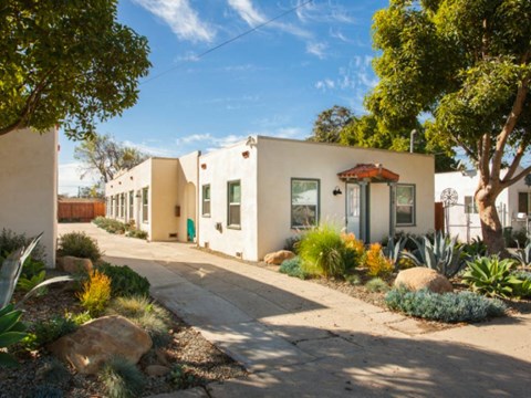 A row of houses with a sidewalk in front.