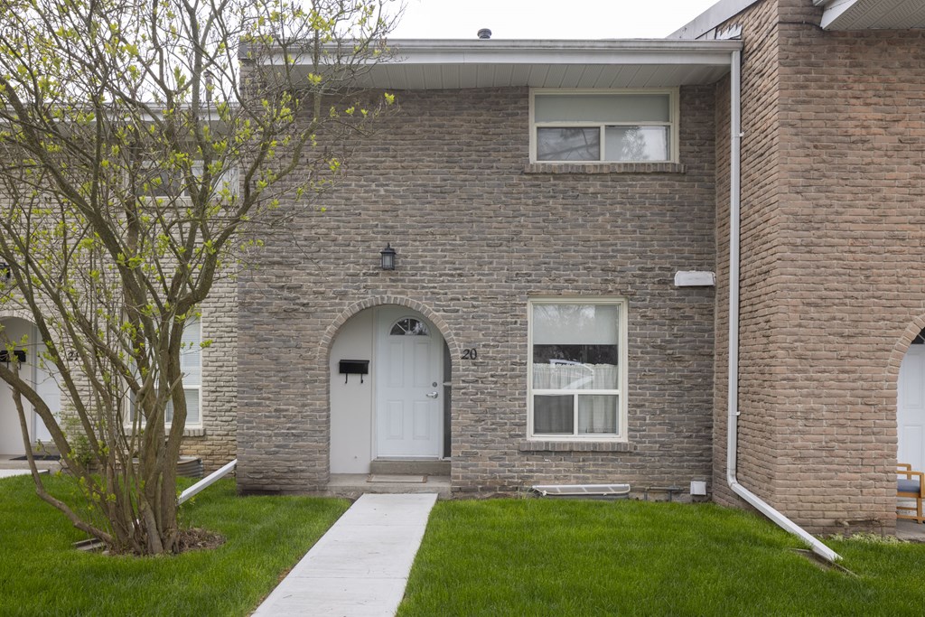 A brick building with a white door, windows, and a front lawn. A brick building with a white door, windows, and a front lawn.