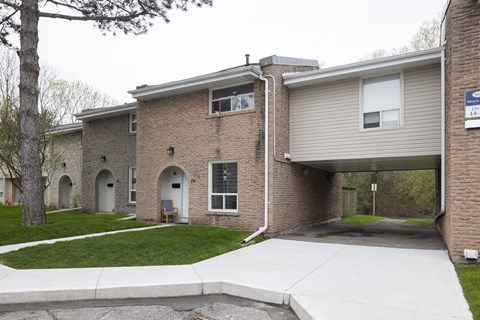 Brick buildings with white doors and a sidewalk in front.