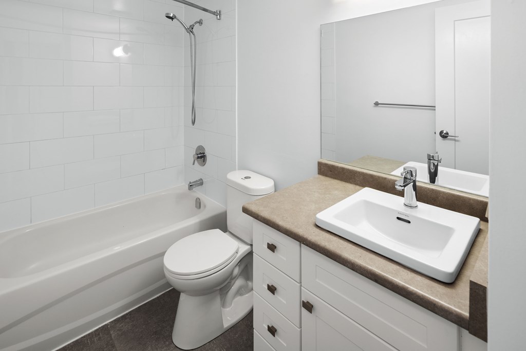 A bathroom with a sink, mirror, toilet, and bathtub.