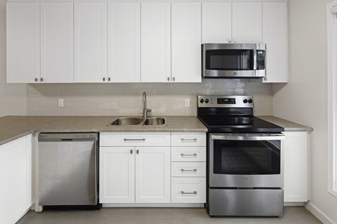 A modern kitchen with white cabinets and stainless steel appliances.