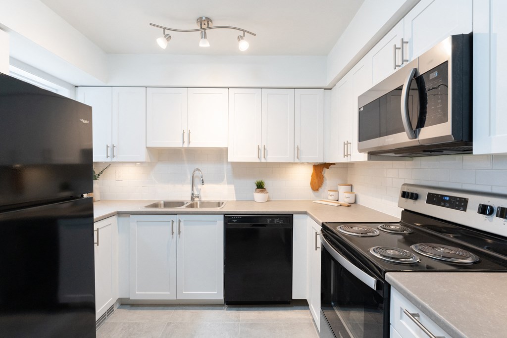 a kitchen with white cabinets and black appliances