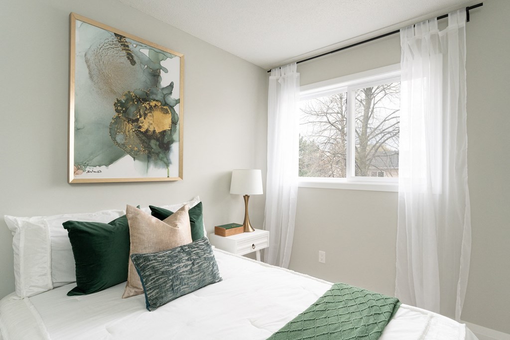 a bedroom with white curtains and green pillows