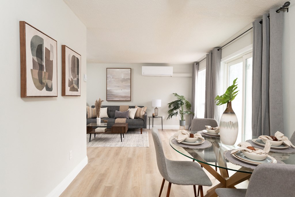 a living room with a glass table and chairs and a couch in the background