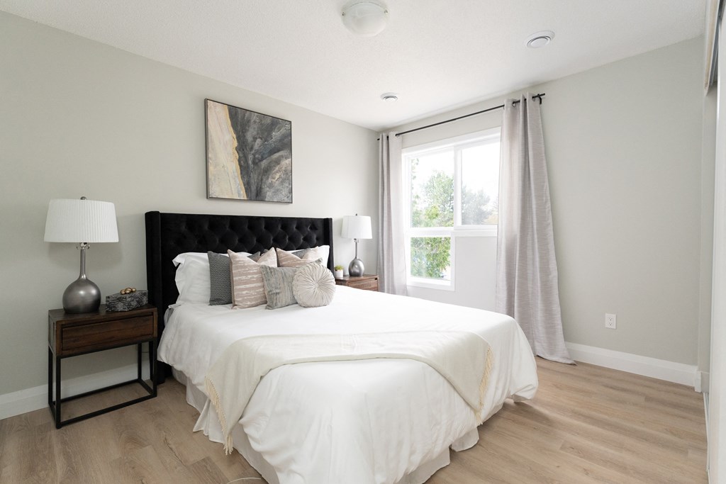 a bedroom with white walls and a large white bed with a black headboard
